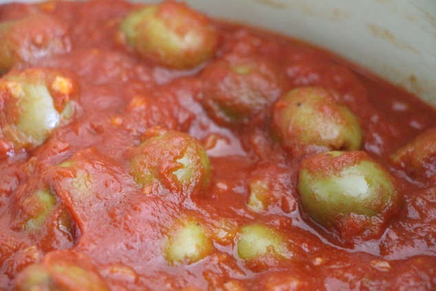 green olives in tomato sauce cooking up close