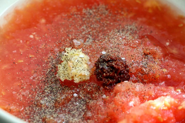 adding harissa and garlic to grated tomatoes