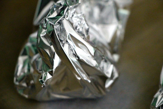 wrapping garlic in aluminum foil up close