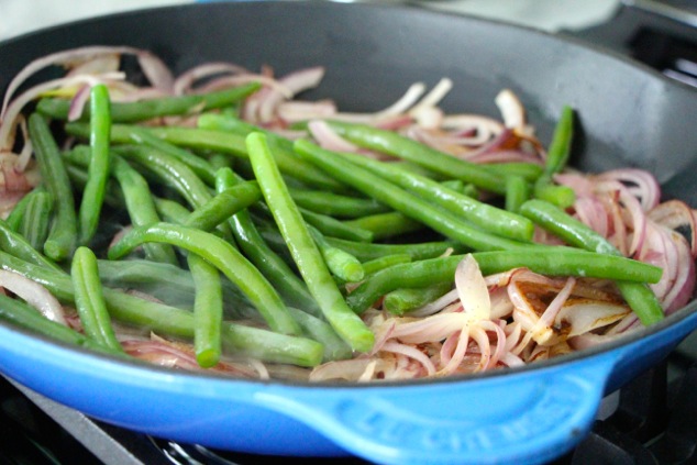 adding blanched green beans to pan