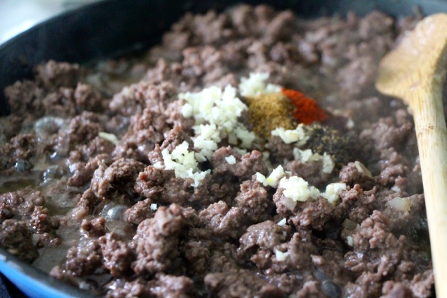 adding garlic and spices to the ground meat