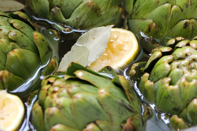 artichokes in pot with lemon water and bay leaf up close