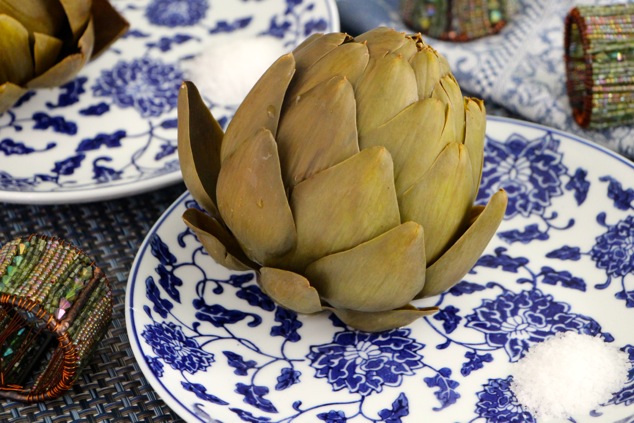 boiled artichokes served on plates with side of salt