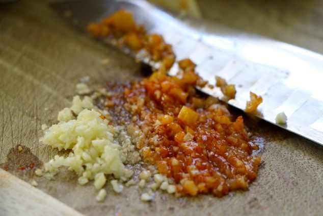 mincing garlic and preserved lemon on cutting board