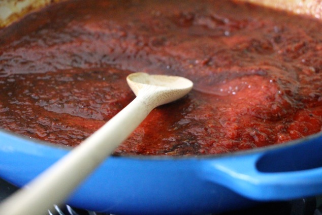 mixing crushed tomatoes into the sauce