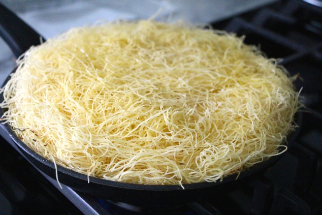 adding a top layer of kadaif pastry to Knafeh