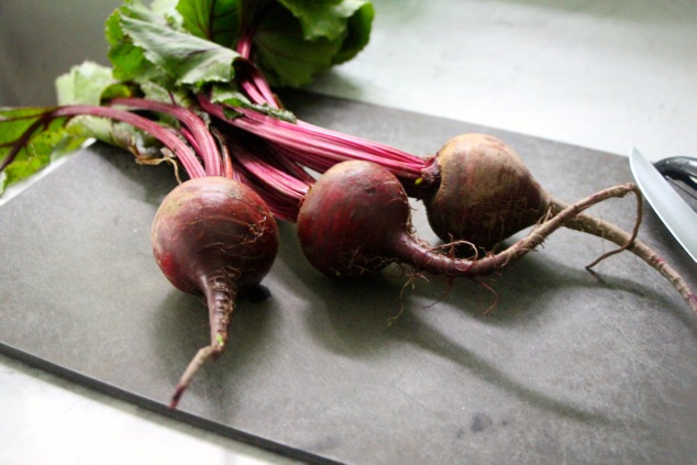 three fresh beets on a cutting board