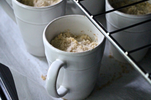 individual crumbles in mugs baking in the oven