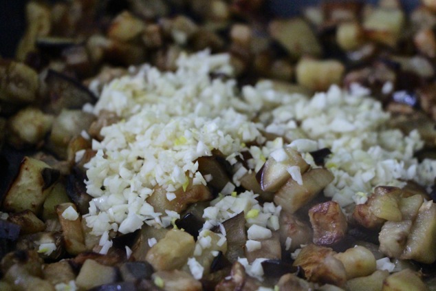 adding chopped garlic to eggplants