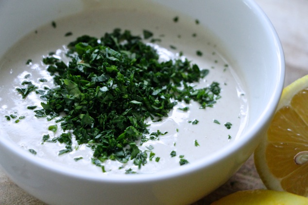 adding chopped parsley to tehina tzatziki