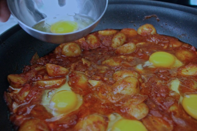 adding eggs to the shakshuka