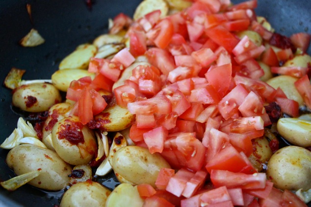 adding tomato cubes to the pan