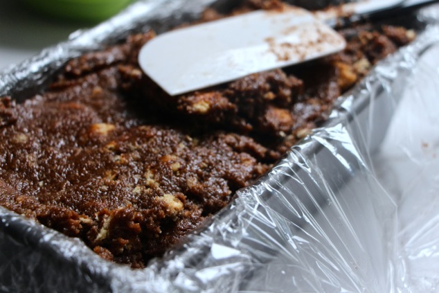 adding graham crackers and fudge mixture into cake pan