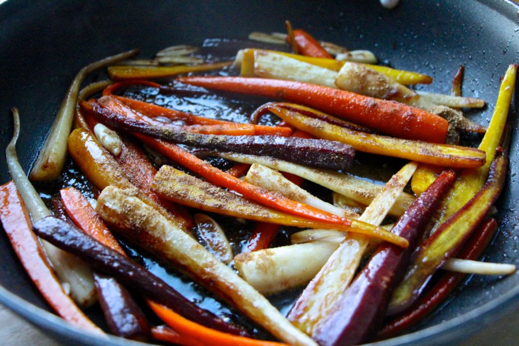 adding cumin to colorful carrots