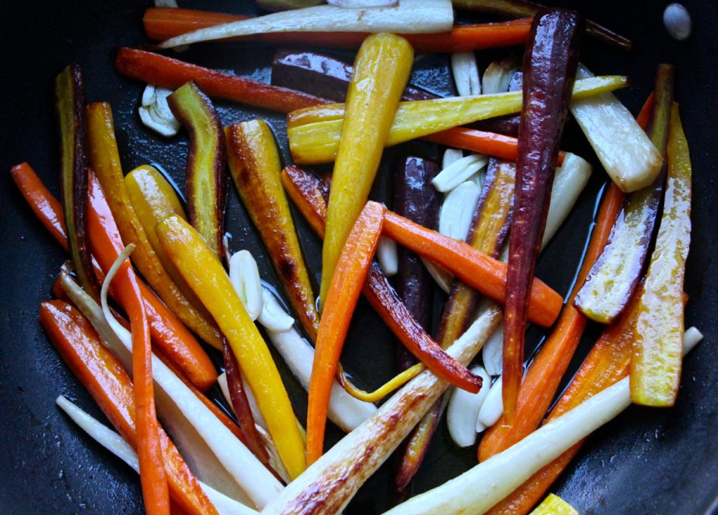 colorful carrots sautéing in pan with garlic